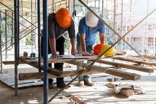 Construction professionals reviewing building plans at a construction site surrounded by scaffolding